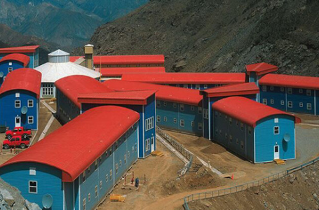 Estructura de vivienda modular con techos rojos y paredes azules, ubicada en un entorno montañoso, ideal para proyectos de construcción rápida. Casa prefabricada que destaca por su diseño funcional y adaptabilidad. Tecno Fast Home.