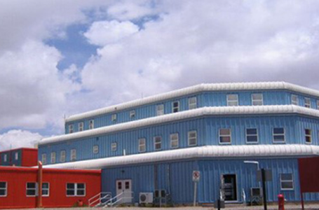 Edificio de vivienda modular de varios niveles, con una fachada en tonos azules y rojos, diseñado para ofrecer espacios habitables eficientes y funcionales. Ideal para quienes buscan una solución rápida y moderna en el ámbito de la construcción. Marca Tecno Fast Home.