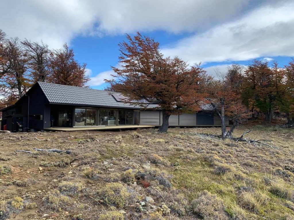Casa modular moderna situada en un entorno natural, rodeada de árboles y con un diseño que integra espacios al aire libre. Ideal como segunda vivienda o refugio, esta vivienda prefabricada ofrece confort y funcionalidad. Marca: Tecno Fast Home.