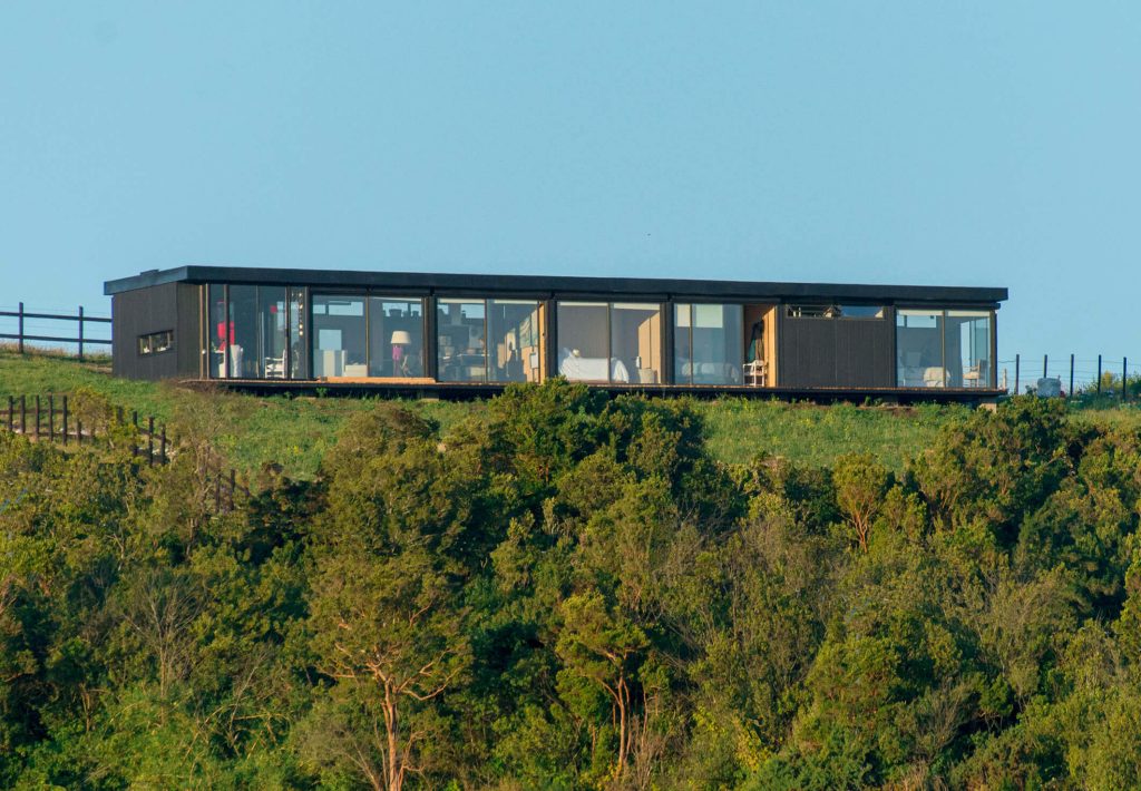 Casa modular contemporánea ubicada en un entorno natural, con amplios ventanales que ofrecen vistas panorámicas. Ideal como vivienda principal o segunda vivienda para disfrutar de la naturaleza. Diseño elegante y funcional. Marca Tecno Fast Home.