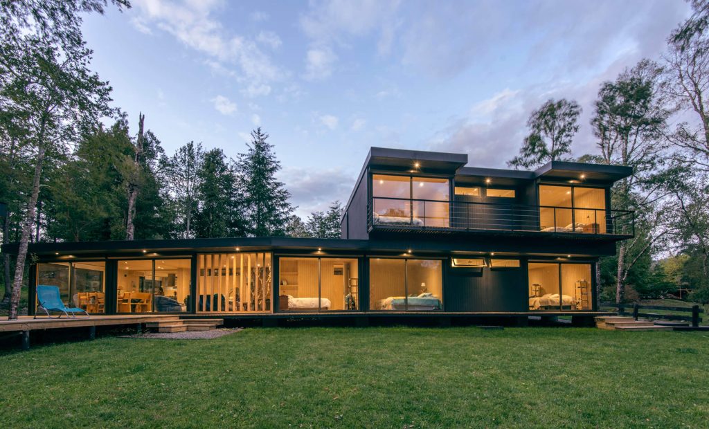 Casa modular contemporánea con amplios ventanales y diseño moderno, ubicada en un entorno natural. Ideal como vivienda principal o segunda vivienda. Construcción eficiente y rápida. Tecno Fast Home.