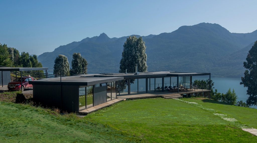 Casa modular moderna ubicada junto a un lago, con amplios ventanales y un diseño contemporáneo que se integra con la naturaleza. Ideal como vivienda permanente o segunda vivienda. Marca Tecno Fast Home.