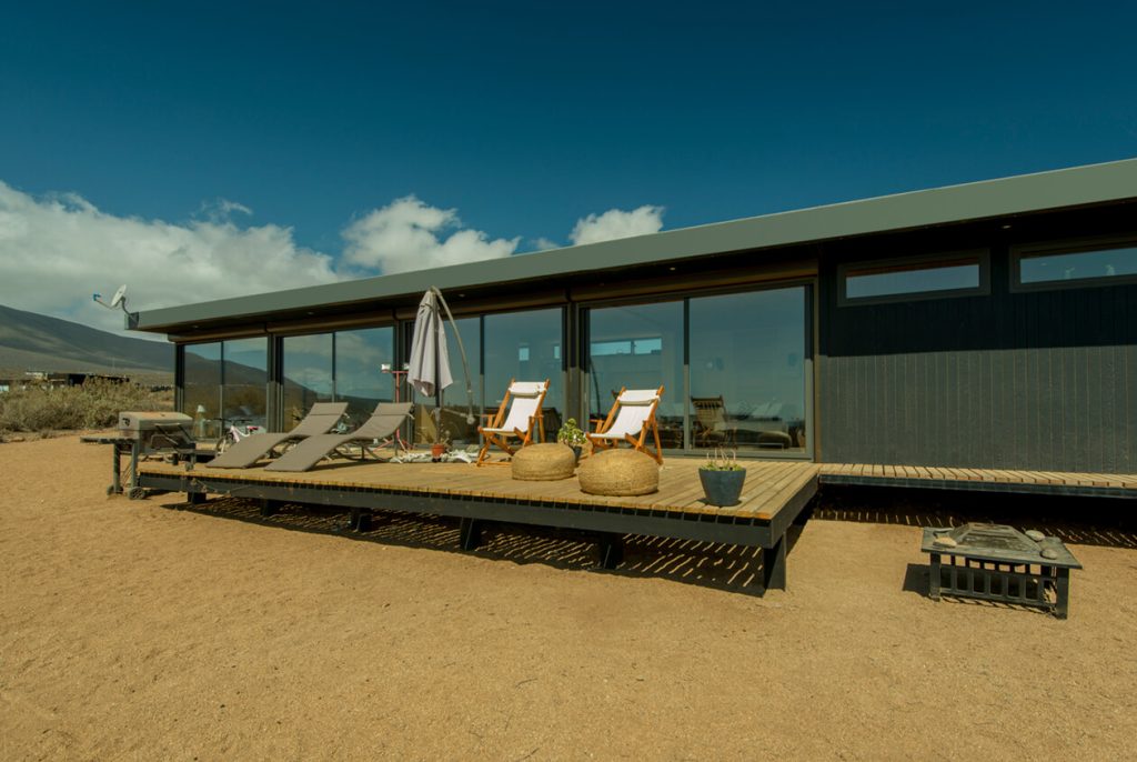 Casa modular moderna con amplia terraza y mobiliario exterior, ideal para disfrutar del aire libre. Diseño contemporáneo y funcional, perfecta como vivienda principal o segunda vivienda. Tecno Fast Home.