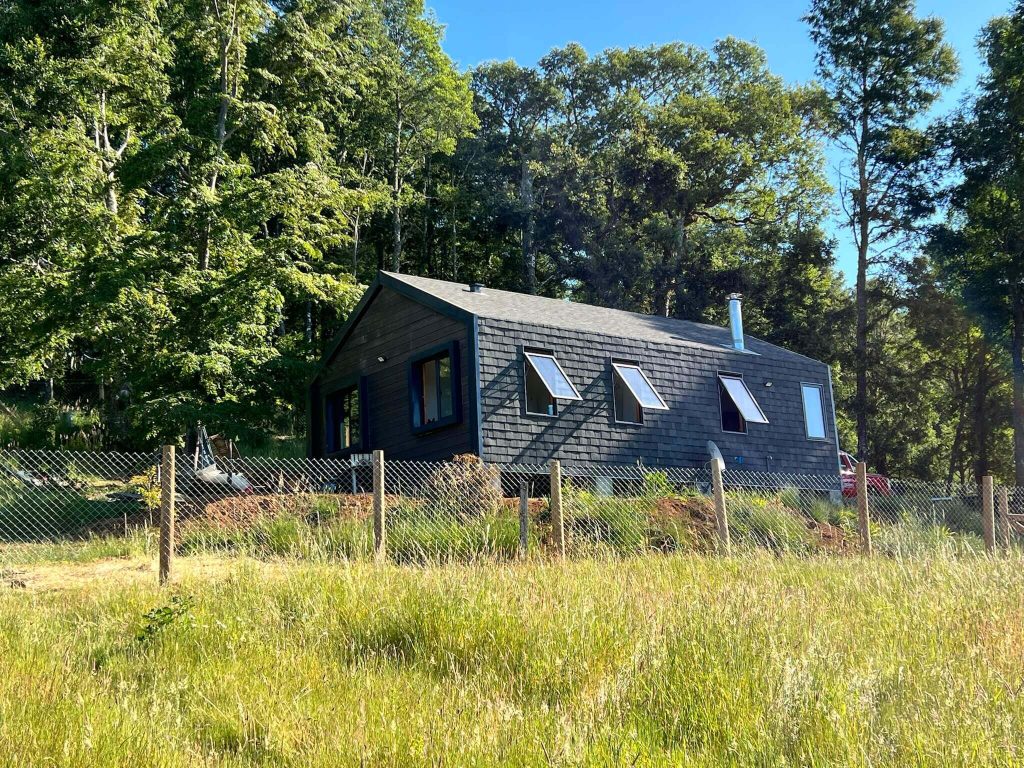 Casa modular rodeada de naturaleza, con un diseño contemporáneo y amplios ventanales que permiten la entrada de luz natural. Ideal como segunda vivienda o refugio. Construcción eficiente y sostenible. Marca Tecno Fast Home.