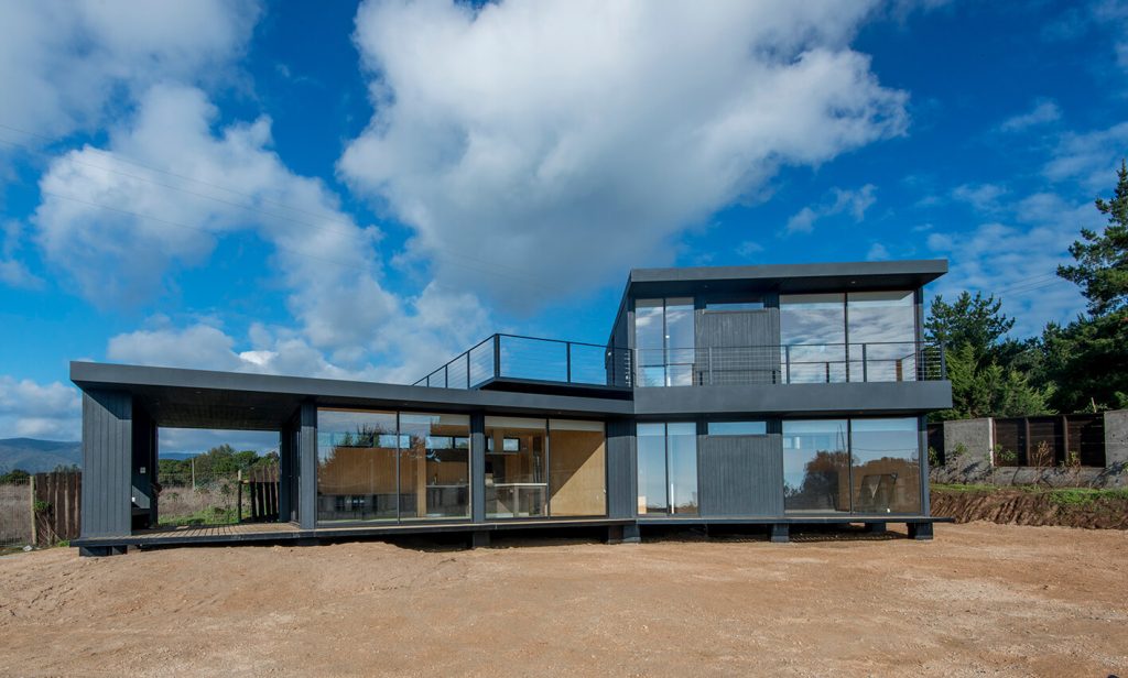 Casa modular contemporánea con amplios ventanales y terraza al aire libre, ideal para una segunda vivienda. Diseño moderno y funcional que maximiza la luz natural. Marca Tecno Fast Home.