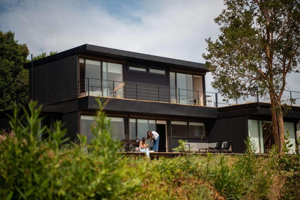 Casa modular moderna rodeada de vegetación, con un diseño contemporáneo y amplios ventanales que ofrecen luminosidad. Ideal como vivienda principal o segunda vivienda. Tecno Fast Home.