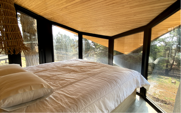 Habitación luminosa con grandes ventanales que ofrecen vistas al exterior, diseñada para una casa modular. Espacio acogedor y moderno ideal para una segunda vivienda. Diseño contemporáneo que maximiza la luz natural. Marca Tecno Fast Home.