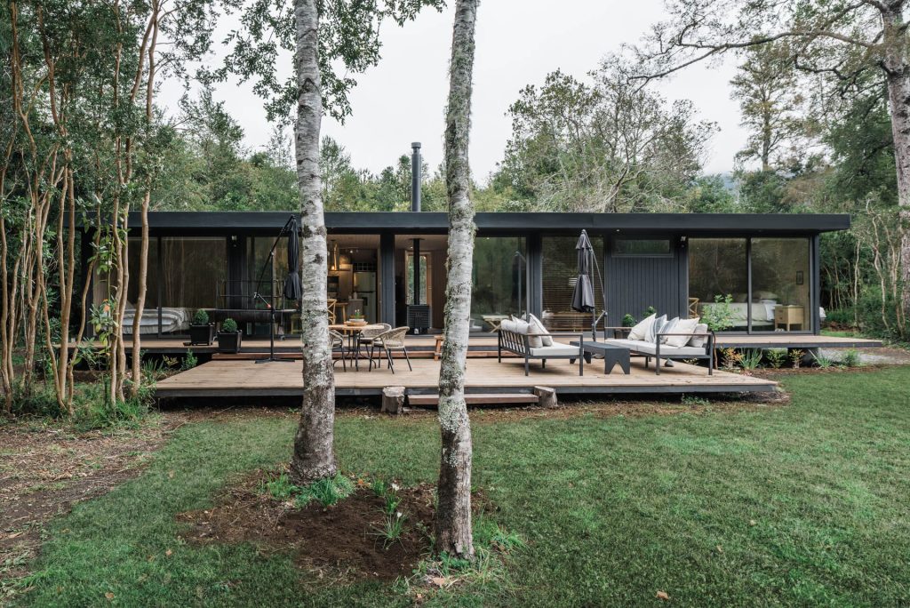 Casa modular rodeada de naturaleza, con un amplio deck de madera y un diseño contemporáneo que invita a disfrutar del entorno. Ideal como segunda vivienda o casa prefabricada. Tecno Fast Home.