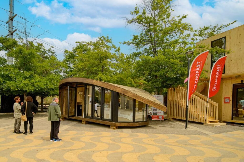 Casa modular con diseño innovador y moderno, ubicada en un entorno natural. Presenta una estructura de madera y amplios ventanales, ideal como vivienda secundaria o casa prefabricada. La marca Tecno Fast Home ofrece soluciones habitacionales de alta calidad.