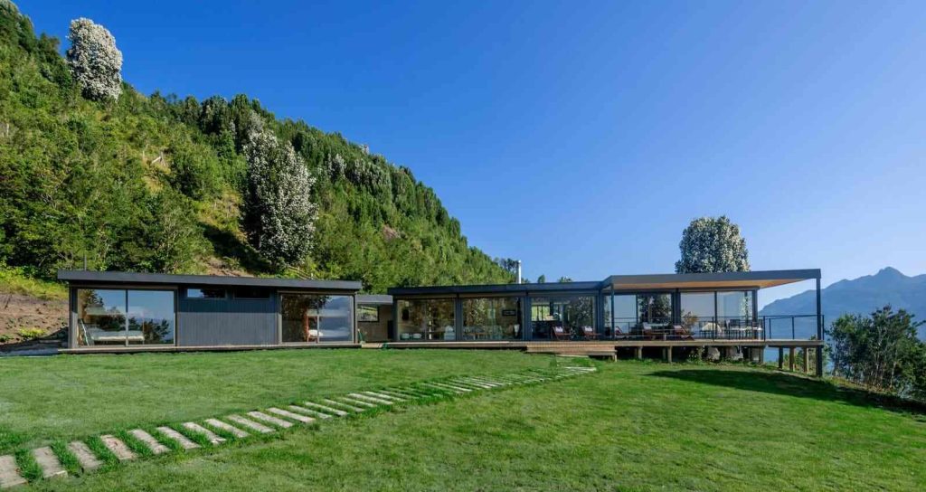 Casa modular contemporánea rodeada de naturaleza, con amplios ventanales que ofrecen vistas panorámicas. Ideal como segunda vivienda o vivienda modular. Diseño elegante y funcional de Tecno Fast Home.