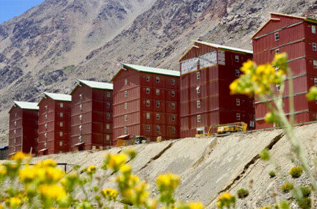 Grupo de casas modulares de color rojo situadas en un entorno montañoso, destacando la funcionalidad y la estética de la vivienda prefabricada. Estas estructuras son ideales para ser utilizadas como segundas viviendas o alojamientos temporales. Marca: Tecno Fast Home.