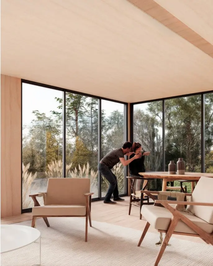 Un acogedor interior de una vivienda modular, donde una pareja disfruta de un momento especial. La amplia ventana permite una vista natural, creando un ambiente cálido y relajante. Este diseño de casa prefabricada combina confort y estilo. Tecno Fast Home.
Un espacio luminoso en una casa modular, con muebles modernos y un ambiente íntimo. La decoración minimalista resalta la conexión con el exterior, ideal para una segunda vivienda. La opción perfecta para quienes buscan un refugio en la naturaleza